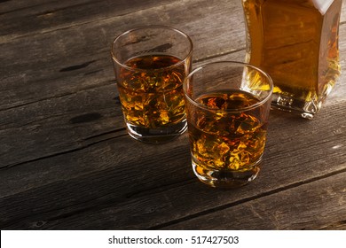 Whisky In Two Glasses On A Dark Wooden Background. Toning.