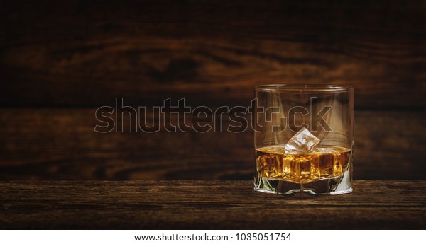 Whisky\
or whiskey or bourbon with ice on wood\
background