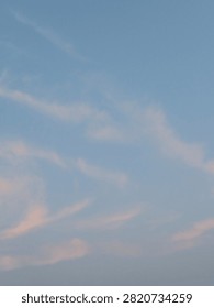 Whispers of pink clouds float across a tranquil blue sky, painting a soft and dreamy moment where peace feels endless.