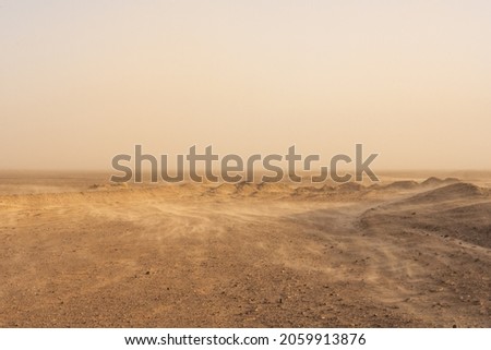 Whisps Of Sand Blow Over The Barren Desert Floor