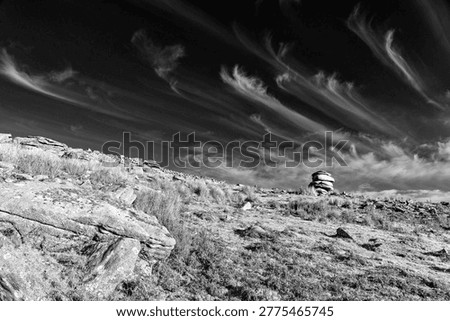 Whispy clouds over the rugged landscape and Granite rock formation known as the Cheesewring near Minions on Bodmin Moor, Cornwall, England, UK 
