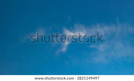 Whispy soft white clouds scattering across deep blue sky atmosphere during daylight