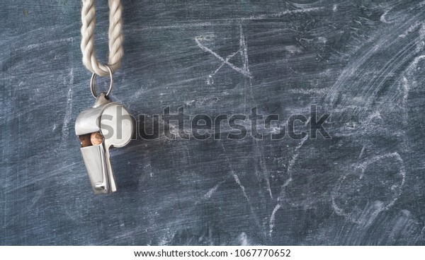 Whistle of a soccer coach or referee on black board\
with free copy space