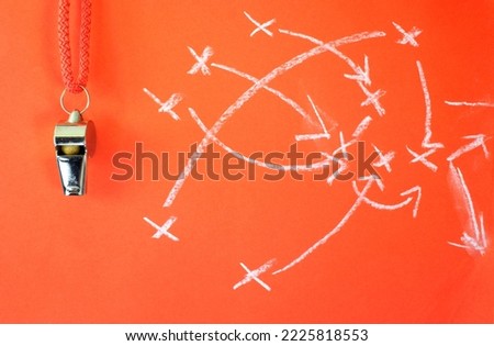 Whistle of soccer referee or trainer and soccer tactics scribble on red background. Great soccer event this year,close up