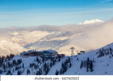Whistler, British Columbia, Canada. Beautiful Panoramic View of Peak to Peak Gondola with the Canadian Snow Covered Mountain Landscape during a cloudy and vibrant winter sunset