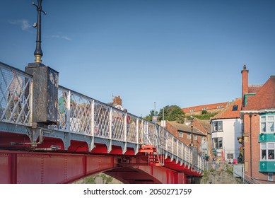 Whitby, UK. September 15, 2021.  Low Angle View Of An Iron Bridge.  People Walk Across And There Is A Public Houses On The Far Side. A Sky With Light Cloud Is Above.