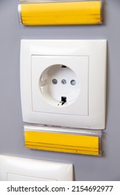 a white 220 volt outlet on a gray wall.