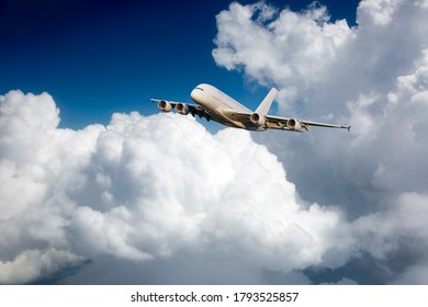 A white 4-engine passenger plane maneuvers between large clouds. Travel and transportation concept.