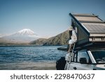 White 4x4 overland car with rooftop tent and awning at the beach and a lake with a view of Mountain Fuji, Japan. 