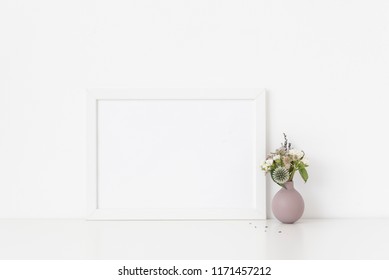 White A4 Landscape Portrait Frame Mockup With Bouquet Of Dried Flowers In Cute Small Vase On White Wall Background. Empty Frame, Poster Mock Up For Presentation Design. Template Frame For Text