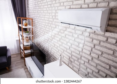 White Air Conditioner Blowing Cold Air On Brick Wall In Living Room