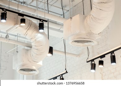 White Air Duct. Ventilation System With Black Down Light Rail. Industrial Styled Interior