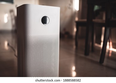 White air purifier placed in the living room inside a house with copy space. Home pollution control and air purification system to remove air borne pollutants.