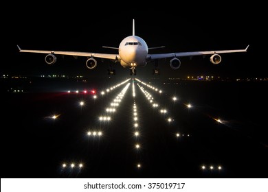 White aircraft takes off from the airport Runaway in the night. Airplane front view.