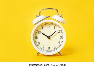 White alarm clock on a yellow background.