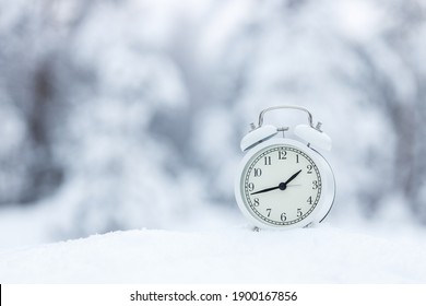 White Alarm Clock In The Winter Snow Forest. The Call Is Set For 3 Oclock In March Spring Is Coming Soon.