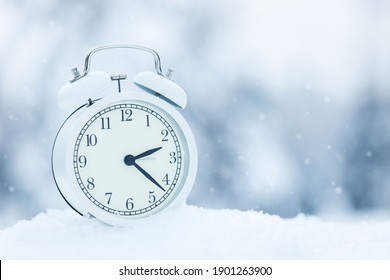 White Alarm Clock In The Winter Snow Forest. The Call Is Set For 3 Oclock In March Spring Is Coming Soon.