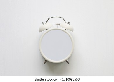 White alarm clock without hands on white background in abstract timeless concept copy space.