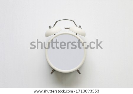 White alarm clock without hands on white background in abstract timeless concept copy space.