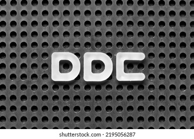 White alphabet letter in word DDC (Abbreviation of Division of disease control,  Direct digital control, Display Data Channel or Dewey Decimal Classification) on black pegboard background