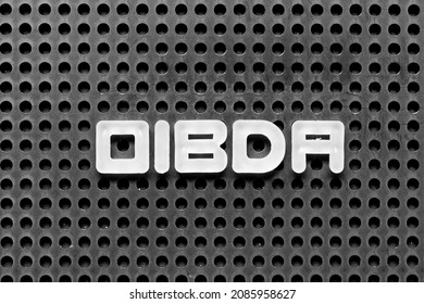White alphabet letter in word OIBDA (Abbreviation of Operating Income Before Depreciation and Amortization) on black pegboard background