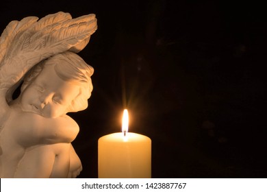 White Angel With A Burning Candle Against A Black Background. Sympathy Card With Lots Of Text To The Right Of The Image.