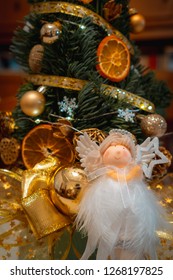 A White Angle Doll Sitting In Front Of A Grinch Tree