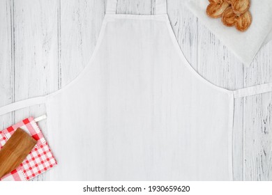 White Apron Template On Wooden Table With Cookies, Copy Space. Kitchen, Cooking Clothing Mockup.