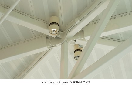 White architectural ceiling structure showcasing intersecting metal beams, perforated acoustic panels, and functional downlights in a modern building interior, highlighting contemporary design and infrastructure.