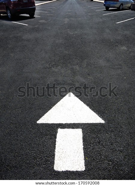 White\
arrow painted on road for cars to follow\
directions