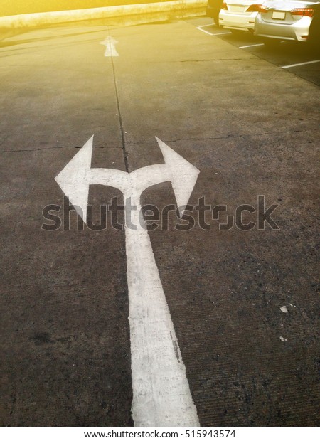 white arrow pointing left and right on ground in a\
car park