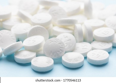 White aspirin pills on blue paper background. Pile of aspirin pills. Medical background