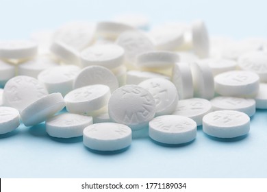 White aspirin pills on blue paper background. Pile of aspirin pills. Medical background