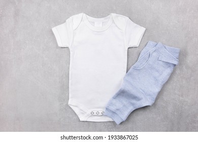 White baby girl or boy bodysuit mockup on the gray concrete background with blue panties. Design onesie template, print presentation mock up. Top view. Flat Lay. 