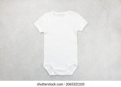 White Baby Girl Or Boy Bodysuit Mockup Flat Lay On The Gray Concrete Background. Design Onesie Template, Print Presentation Mock Up. Top View. 