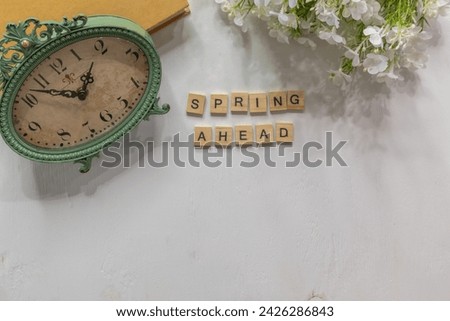 White background with copy space, antique style clock with vintage book and white flowers, Spring ahead for daylight savings time change