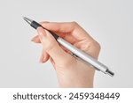 White background with female hand holding black ballpoint pen