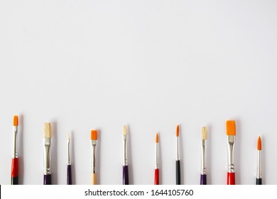 White Background With New Paint Brushes With Place For Text. Art Supplies For Drawing. Quality Materials For Creativity And Hobbies. Brush Frame For Oil And Acrylic Paint.Copy Space With Materials