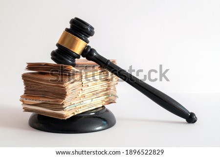 white background on a judge's hammer supported by a large number of banknotes positioned on top of each other
