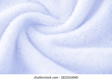 White Background Of Towel Texture Or Cozy Plush Plaid. Fleece Blanket Lies In Twisted Beautiful Folds. Macro Photo Of Terry Cloth Bath Or Beach Towel. Soft Textile Backdrop.