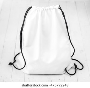 White Backpack With Black String On Planked Surface