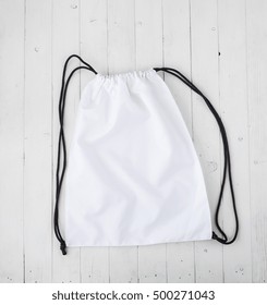 White Backpack With Black String On Planked Surface