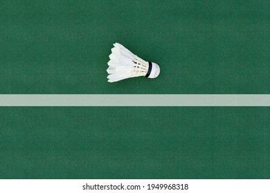 A white badminton feather shuttlecock at a corner on a badminton court.