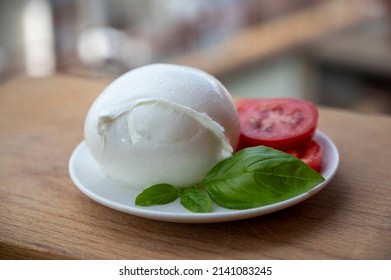 White ball of Italian soft cheese Mozzarella di Bufala Campana served with fresh green basil and red tomato
