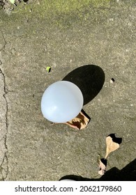 White Balloon On The Ground With White Shoes Next To It