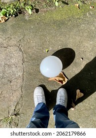 White Balloon On The Ground With White Shoes Next To It