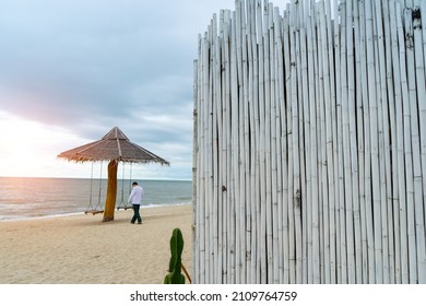 White Bamboo Wood To Arranged Wall  With Alone Man To Walk To Swings With Rope Is Under  Wooden Stand Bower On The Beach And Sunlight Background