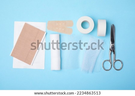 White bandage and medical supplies on light blue background, top view