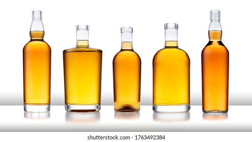 A white bar with a row of bottles full of golden whisky, with no label or branding, isolated on white with a slight reflection - Powered by Shutterstock