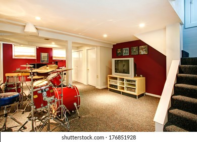 White Basement Room With Red And Burgundy Walls, Carpet Floor. Rehearsal Room With Drums